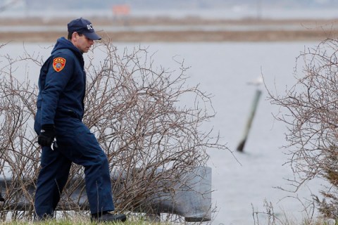 A member of the Suffolk County police search team looks for remains of bodies near the beach area of Oak Beach