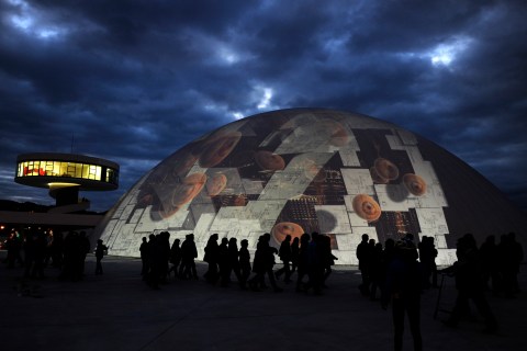 People view the "Organismo", an art installation by Spanish artist Marina Nunez, being projected on the Niemeyer Center dome in Aviles