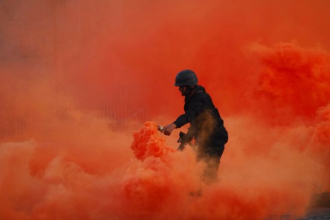 An Indian Navy soldier dispenses smoke from a canister during a dress rehearsal ahead of Navy Day celebrations in Mumbai