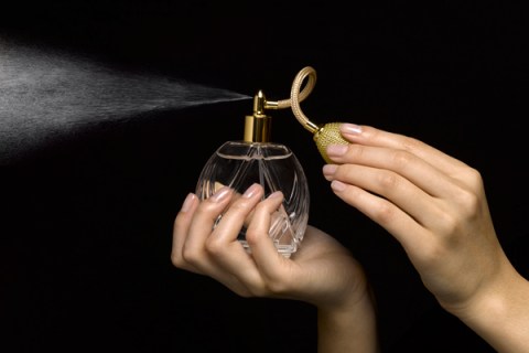 Woman spraying perfume with perfume atomizer, close-up of hands