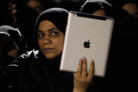 An anti-government protester films with her iPad during an al-Wefaq rally in Sanabis