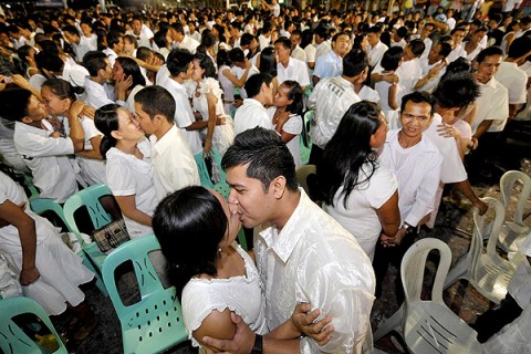 Newly-wed couples embrace at a mass ceremony