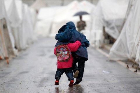 Syrian boys walk shoulder to shoulder in the rain at the Boynuyogun refugee camp on the Turkish-Syrian border in Hatay province