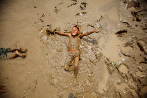 A boy plays in the mud on the bank of the Bago river in Bago