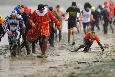 Competitors run in the rain along the banks of a the Blackwater River at low tide during the Maldon Mud Race  in Maldon