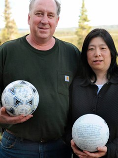 David Baxter and his Japanese wife Yumi pose with a soccer ball which they found at a remote site in the Gulf of Alaska