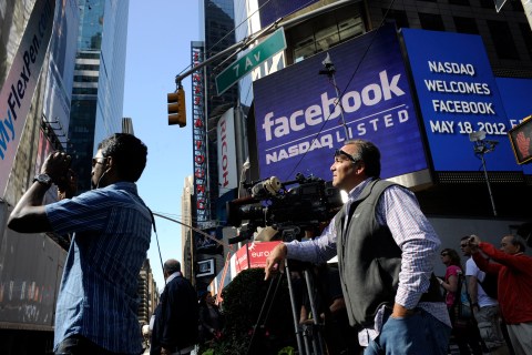 Pedestrians and media  near the NASDAQ Marketsite at the start of the listing for Facebook in New York