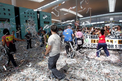 Cleaning staff workers toss pieces of papers during a protest at Barcelona's airport