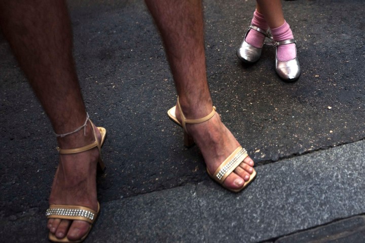 A girl stands next to a contestant before the annual race on high heels during Gay Pride celebrations in the quarter of Chueca in Madrid