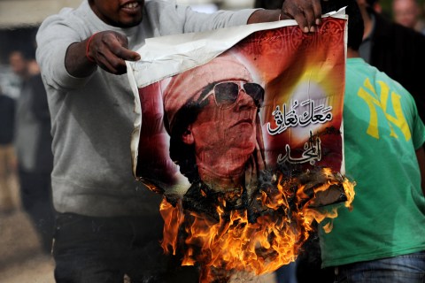 A man holds a burning poster of Libyan strongman Muammar Gaddafi in Benghazi in March of 2011.