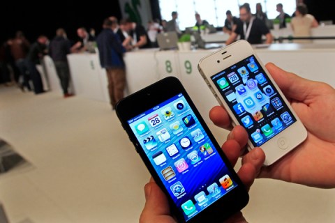 A customer holds up an Apple iPhone 5 and iPhone 4s
