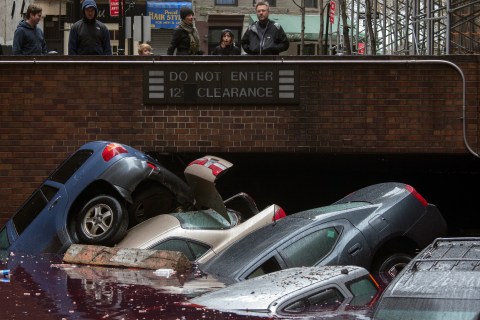 Residents stand over vehicles which were submerged in a parking structure in the financial district of Lower Manhattan, New York