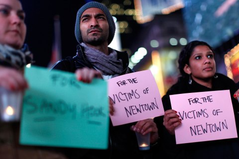image: People hold a candlelight vigil in Times Square, for the victims of the Sandy Hook School shooting, in New York
