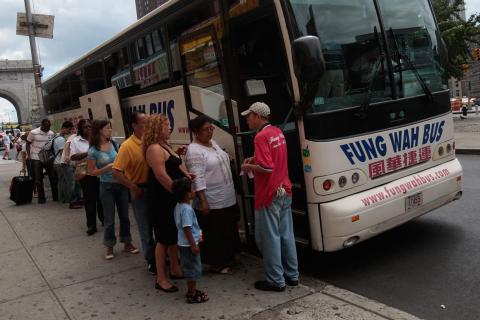 img: Passengers line up to board a Fung Wah bus headed for Boston on August 4, 2008 in New York City.
