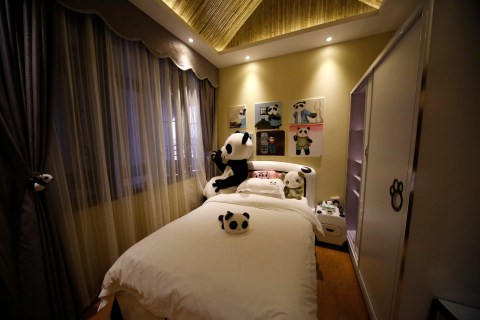 An employee dressed in a panda costume poses for a photo during the soft opening of a panda-themed hotel at the foot of Emei Mountain