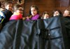Children demonstrate how they might take shelter in a school under a bullet proof blanket sold by Elite Sterling Security LLC in Aurora