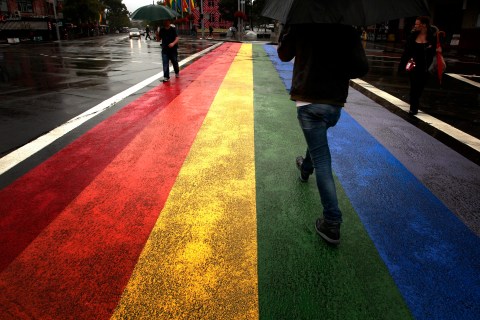 People walk across a rainbow pedestrian crossing painted on Sydney's Oxford street