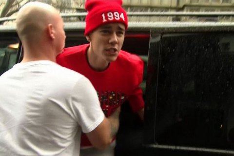 Justin Bieber is held back by a member of his security team as he confronts a photographer outside his hotel in central London