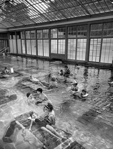 Polio patients with physical therapist being given "muscle re-education" in swimming pool at FDR's Warm Springs Foundation complex, the incredible facility for boarding and treating the young and old victims of polio.