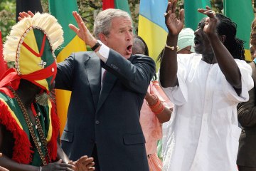 Former U.S. President George W. Bush dances with members of the Kankouran West African Dance Company in the Rose Garden of the White House in Washington, D.C., on April 25, 2007.
