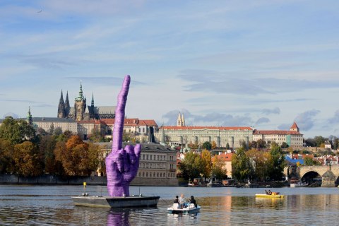 People sailing on the boats on Vltava River look at the giant purple middle finger sculpture by Czech artist David Cerny on October 21, 2013 in Prague. 