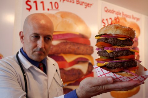 Heart Attack Grill owner Jon poses with a quadruple bypass cheese burger in Chandler, Arizona