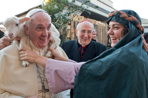 A woman dressed as a character from the nativity scene puts a lamb around the neck of Pope Francis as he arrives to visit the Church of St Alfonso Maria dei Liguori in the outskirts of Rome, on Jan. 6, 2014.