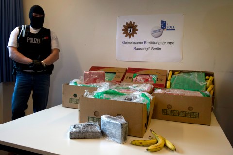 A masked poliman stands next to banana crates with confiscated drugs in the police headquarters in Berlin, Tuesday Jan.7, 2014.