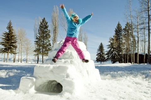 Young girl jumping next to an igloo