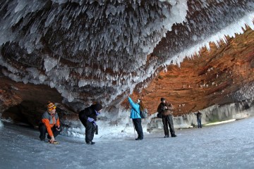 Sightseers crouch to avoid icicles in a sea cave on frozen Lake Superior at the Apostle Islands National Lakeshore