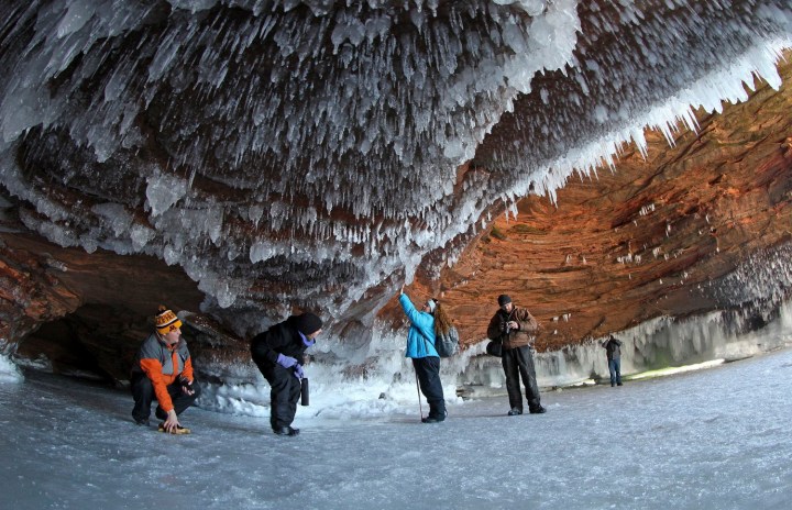 Sightseers crouch to avoid icicles in a sea cave on frozen Lake Superior at the Apostle Islands National Lakeshore