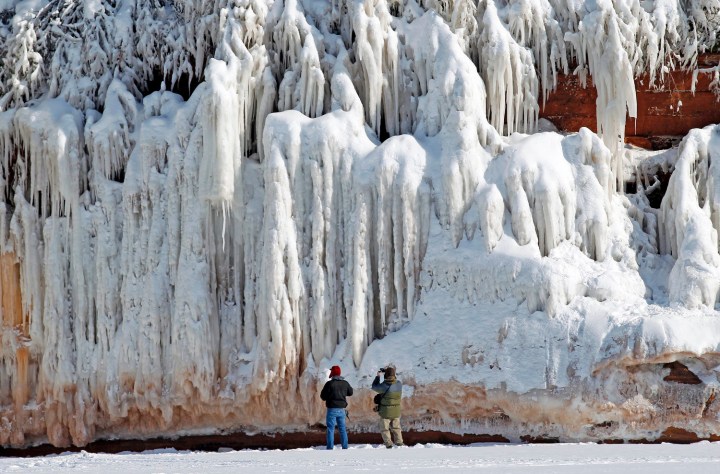 Sightseers look at a frozen rock face along the Apostle Islands National Lakeshore of Lake Superior