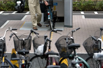 A MAN TAKES A BICYCLE OUT OF THE "ECO CYCLE" PARKING IN TOKYO.